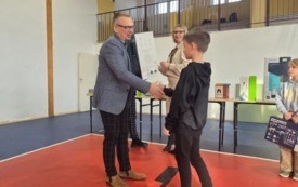 burmistrz wręcza nagrody dla ucznia na sali gimnastycznej