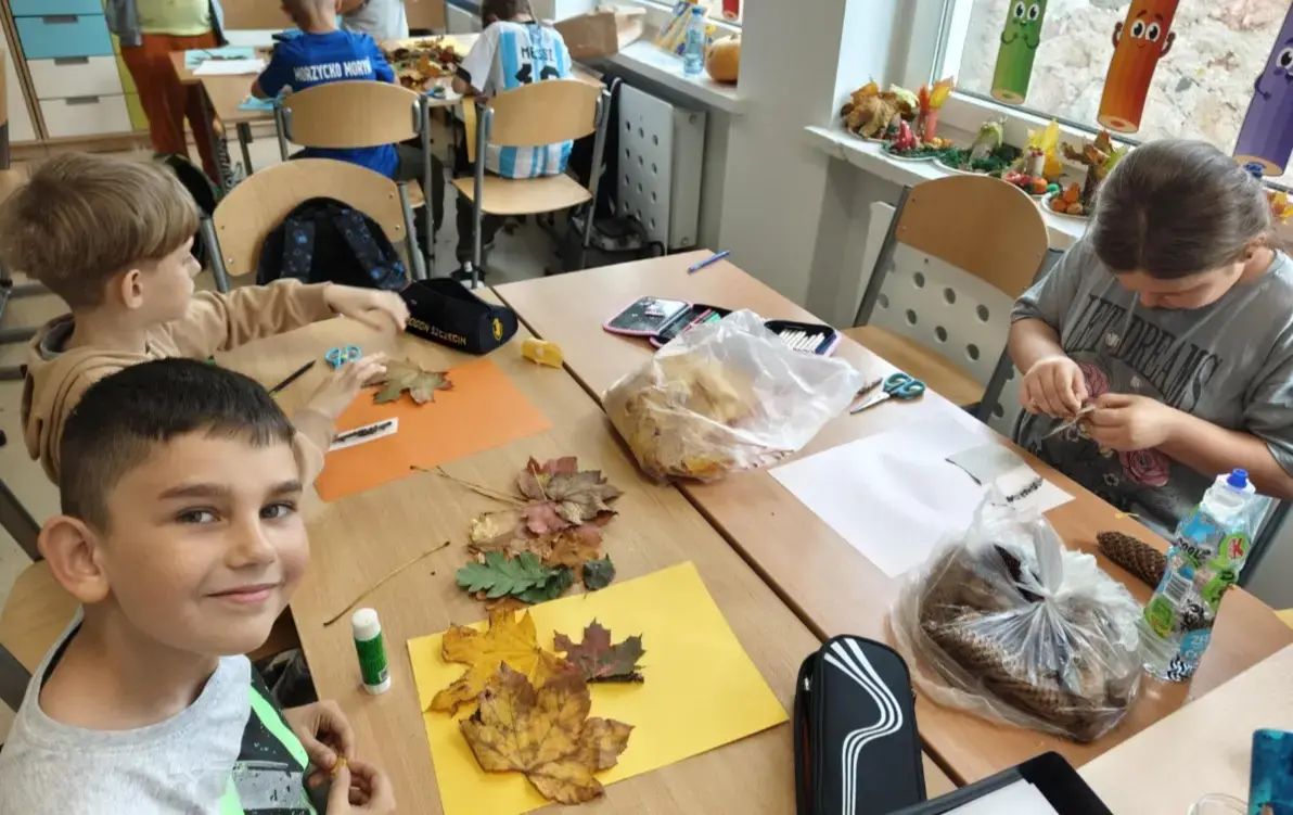 Dzieci przy stolikach wykonujące prace plastyczne