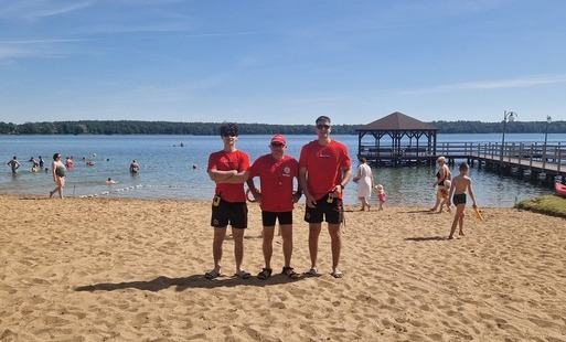Zdjęcie przedstawiajace trzech ratowników stojących na plaży